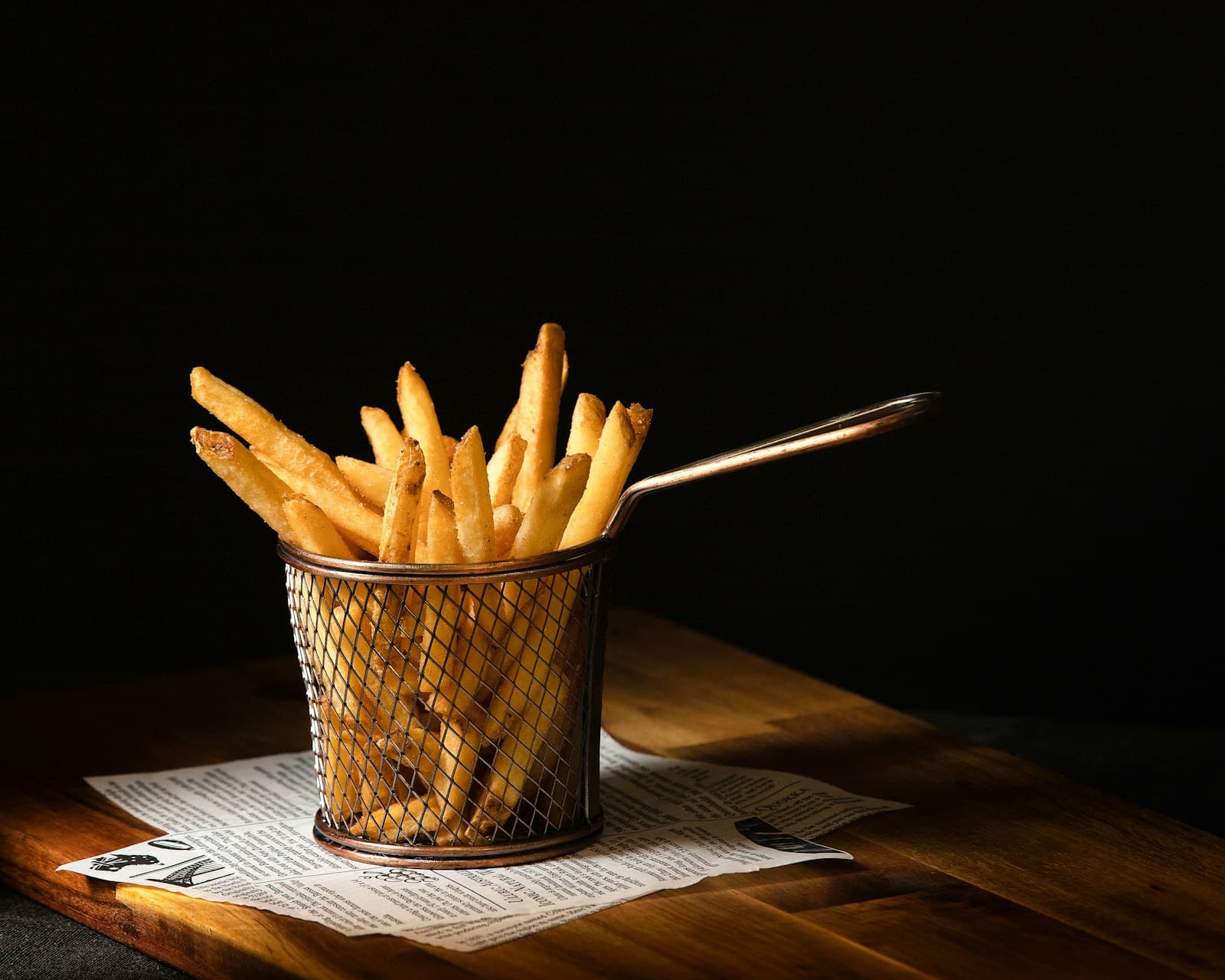 Basket of seasoned fries on a dark wooden table